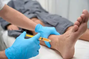 Orthopedic surgeon injecting patient's ankle with PRP